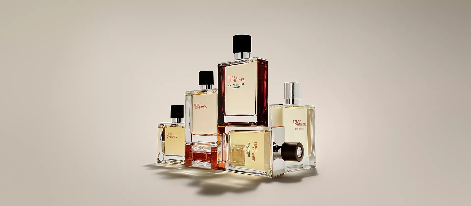 A collection of Hermès perfumes arranged on a warm neutral background